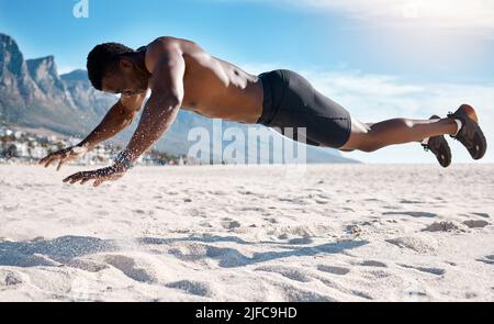Fit jungen schwarzen Mann macht Plank Hold Übungen auf Sand am Strand am Morgen. Afroamerikanischer muskulöser männlicher Bodybuilder Athlet tut Stockfoto