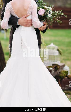 Schöne Braut steht mit Bräutigam in Umarmungen Stockfoto