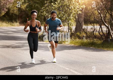 Fit afroamerikanischen Paar läuft im Freien während des Trainings. Junge sportliche Mann und Frau Training, um ihre Cardio-und Ausdauer für eine zu verbessern Stockfoto
