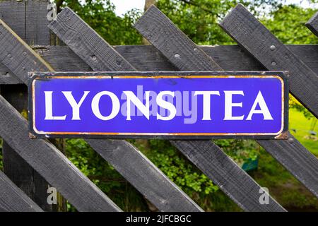 Pickering, Großbritannien - 9. 2022. Juni: Nahaufnahme eines alten Lyons-Tee-Schildes, auf einem Zaun am Pickering Railway Station in North Yorkshire, Großbritannien. Stockfoto