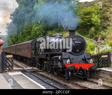 Goathland, Großbritannien - 9. 2022. Juni: Ein klassischer Dampfzug der North Yorkshire Moors Railway, der in den Goathland Railway Station in North Yorkshire fährt, Stockfoto