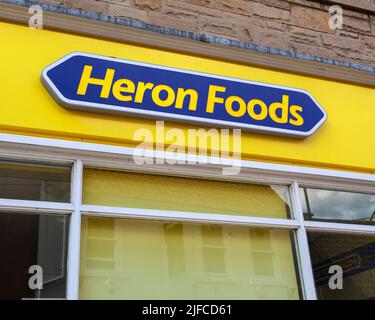 Whitby, Großbritannien - 10. 2022. Juni: Logo der Heron Foods-Firma über dem Eingang zu einem ihrer Geschäfte in Whitby, North Yorkshire, Großbritannien. Stockfoto