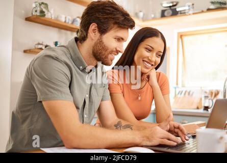 Junge glücklich interracial paar Bonding beim Tippen auf einem Laptop zusammen zu Hause. Kaukasischen Freund und Freundin arbeiten durch ihre Rechnungen und Stockfoto