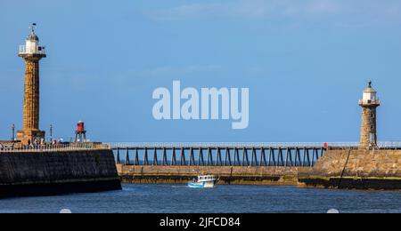 Whitby, Großbritannien - 10. 2022. Juni: Ein Boot fährt in Whitby Harbour zwischen den East und West Lighthouses in Whitby, North Yorkshire. Stockfoto