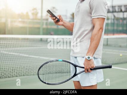 Unbekannter gemischter Tennisspieler mit Mobiltelefon während der Spielpause auf dem Platz zum Text. Hispanic fit Athlet Surfen im Internet und Networking am Telefon Stockfoto