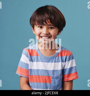 Porträt eines niedlichen kleinen asiatischen Jungen in legerer Kleidung, während sie lächeln und aufgeregt aussehen. Kind steht vor blauem Studiohintergrund Stockfoto