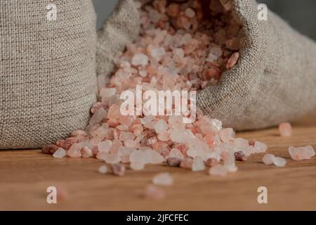 Salzpreis. Große Kristalle aus rosa Himalaya-Salz, Nahaufnahme. Eine Münze in einem Salzhaufen als Symbol für steigende Preise. Stockfoto