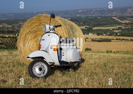 Bild eines alten Piaggio vespa Motorrades auf einem Feld mit Strohballen. Datum 29-06-2022 Toskana Florenz Italien Stockfoto