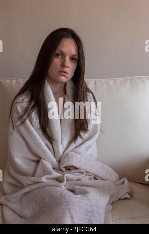Traurige, müde Frau, die auf einem Sofa sitzt Stockfoto