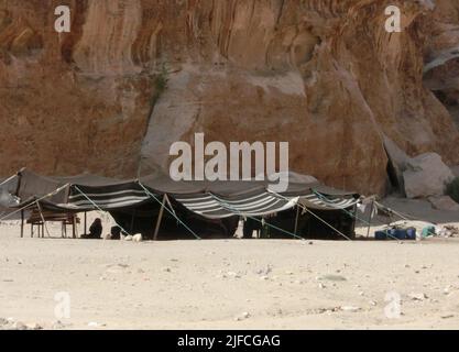 Zelte eines kleinen Lagers eines nomadischen Stammes in der Nähe der Felsen in der Wüste aus Sand Stockfoto