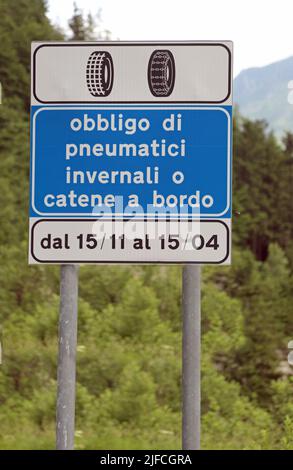 Straßenschild mit der Schrift in italienischer Sprache, die Verpflichtung von Winterreifen oder Schneeketten an Bord von November bis April bedeutet Stockfoto