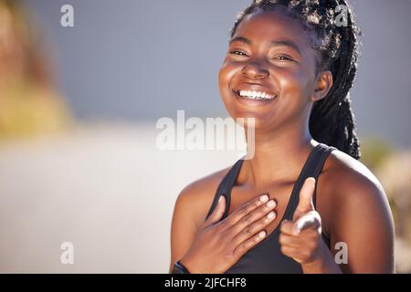 Eine glückliche junge, fit afroamerikanische Frau, die allein steht und zeigt, während sie sich nach einem Training sicher fühlt. Fit und aktive schwarze Frau mit Zöpfen Stockfoto
