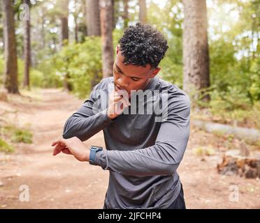 Der afroamerikanische Mann überprüft seinen Puls, während er eine Smartwatch trägt und seinen Puls, seinen Herzschlag und seine Cardio-Gesundheit verfolgt. Sportler, der ein Gerät verwendet, um zu behalten Stockfoto