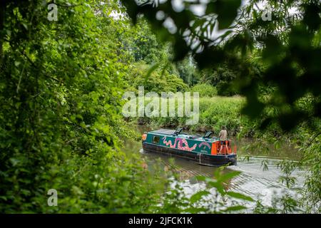 An einem sonnigen Sommertag fährt ein Hausboot entlang des Flusses Avon in Richtung Bath durch den Conham River Park im Osten von Bristol. Stockfoto