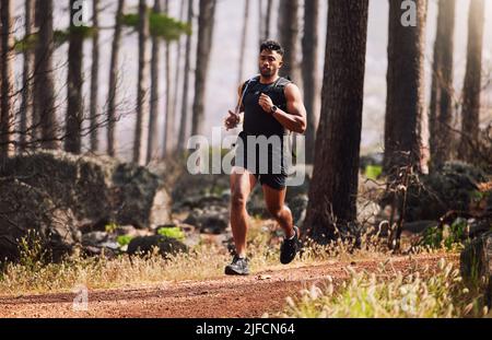 Schöner, athletischer, gemischter junger Mann, der draußen im Wald läuft. Gesunder und sportlicher Athlet zum Joggen in der Wildnis. Einsteigen Stockfoto