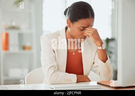 Eine ängstliche junge hispanische Geschäftsfrau, die bei der Arbeit an einem Computer in einem Büro unter Kopfschmerzen leidet. Unternehmer fühlt sich überfordert, müde Stockfoto