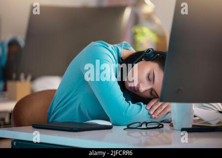 Ein junger kaukasischer Callcenter-Telemarketing-Agent, der in einem Büro schläft. Geschäftsfrau fühlt sich während des Betriebs überfordert, müde und demotiviert Stockfoto