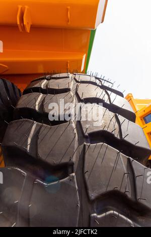 Riesige Hinterräder des Muldenkipper in ungewöhnlichem Winkel aus der Nähe. Die Räder haben eine Lauffläche für die Bewegung des Muldenkipper auf lockerem Boden. Stockfoto