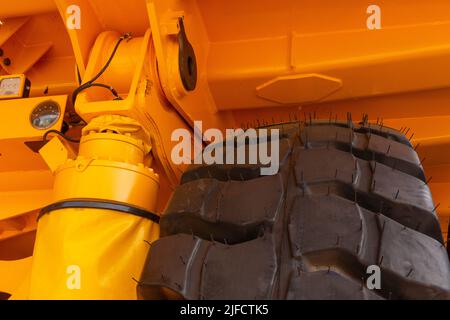 Riesige Hinterräder des Muldenkipper in ungewöhnlichem Winkel aus der Nähe. Die Räder haben eine Lauffläche für die Bewegung des Muldenkipper auf lockerem Boden. Stockfoto