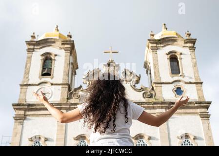 Porträt einer Frau mit dem Rücken zur Kirche. Salvador, Bahia, Brasilien. Stockfoto