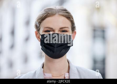 Eine junge Frau, die in der Stadt eine Gesichtsmaske trägt. Eine junge Frau, die in der Stadt eine Gesichtsmaske trägt. Stockfoto