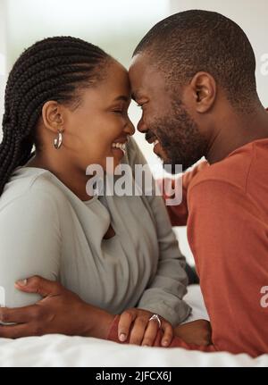 Nahaufnahme eines liebenden afroamerikanischen Paares, das die Stirn berührt, während es auf einem Bett liegt. Glücklicher junger Mann und Frau teilen romantische intime Stockfoto