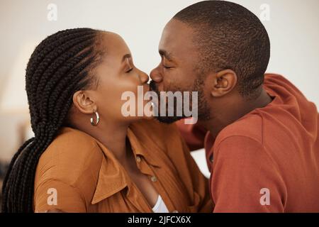 Nahaufnahme eines liebenden afroamerikanischen Paares, das einen leidenschaftlichen Kuss teilt, während es auf einem Bett liegt. Glücklicher junger Mann und Frau teilen romantisch Stockfoto