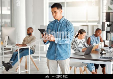 Konzentrierter gemischter Geschäftsmann, der bei der Arbeit an einem digitalen Tablet arbeitet. Seriöser hispanischer Mann, der soziale Medien auf einem digitalen Tablet nutzt. Geschäftsleute Stockfoto