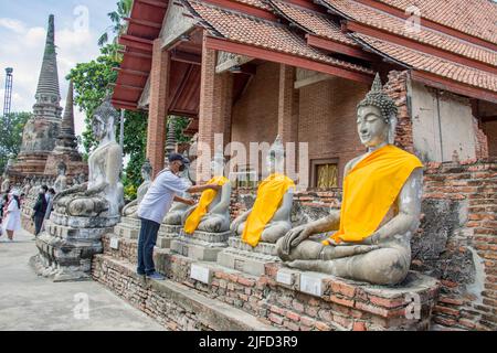 Ayutthaya Thailand 5. Jun 2022: Der Anhänger weihte eine gelbe Kasaya an die Buddha-Statue im Wat Yai Chai Mongkhon , einem buddhistischen Tempel. Stockfoto