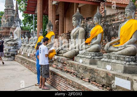 Ayutthaya Thailand 5. Jun 2022: Der Anhänger weihte eine gelbe Kasaya an die Buddha-Statue im Wat Yai Chai Mongkhon , einem buddhistischen Tempel. Stockfoto