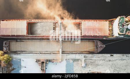Draufsicht von der Drohne eines großen Schiffes, das Getreide für den Export verladen soll. Wassertransport Stockfoto
