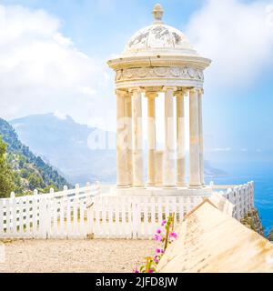 Marmortempel Son Marroig auf einer umzäunten Plattform mit einer Wand und rosa Blumen vor der nordwestlichen Küste Mallorcas in den Bergen der Serra de Tramuntana Stockfoto