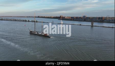 Amsterdam, 21.. april 2022, Niederlande. Zwei Schiffe, die auf der Freiwasserantenne über dem Wasser segeln, folgen dem Segelboot und der Transportschiffyacht Stockfoto