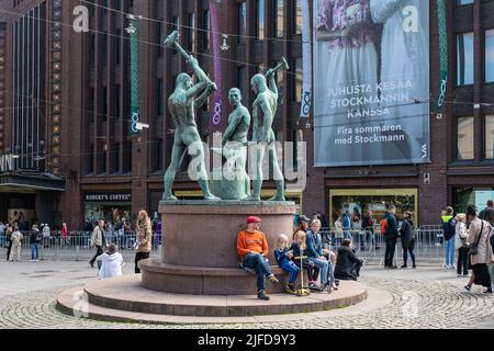 Menschen, die in Kolmen sepän patsa oder der Skulptur Three Smiths von Felix Nylund (1932) in Helsinki, Finnland, ruhen Stockfoto