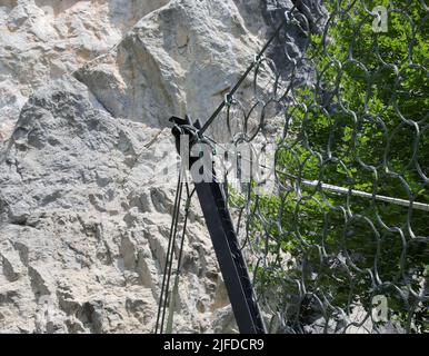 Detail aus robustem Metallgeflecht zum Schutz vor fallenden Felsen und Felsbrocken am felsigen Hang in den Bergen Stockfoto