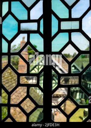 Der verschwommene Blick durch ein Glasfenster aus dem 16.. Jahrhundert in der Little Moreton Hall, einem Fachwerkhaus im Tudor-Herrenhaus in der Nähe von Congleton in Cheshire, Nordwesten E Stockfoto