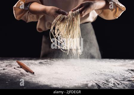 Ausschütteln der geschnittenen Nudeln, der Prozess der Herstellung der traditionellen chinesischen Küche handgerollte Nudeln - Stock Foto Stockfoto