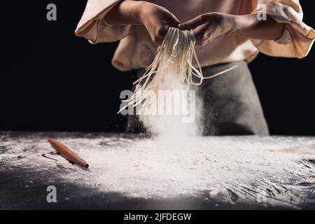 Ausschütteln der geschnittenen Nudeln, der Prozess der Herstellung der traditionellen chinesischen Küche handgerollte Nudeln - Stock Foto Stockfoto