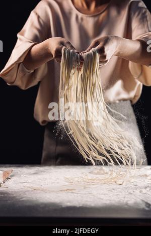 Ausschütteln der geschnittenen Nudeln, der Prozess der Herstellung der traditionellen chinesischen Küche handgerollte Nudeln - Stock Foto Stockfoto