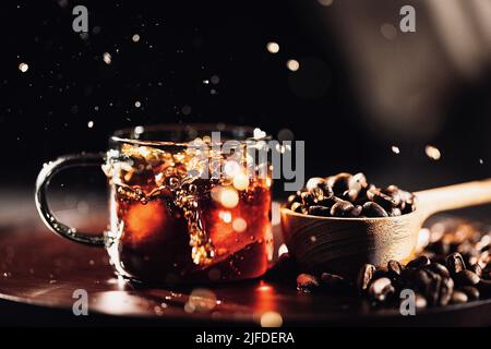 Hinzufügen von Eiswürfeln zu schwarzem Kaffee, der traditionellen handwerklichen Kaffeeherstellung - Stock photo Stockfoto
