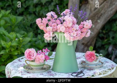 Romantisches Arrangement mit Bouquet aus rosa Rosen und Vintage-Kaffeetassen Stockfoto