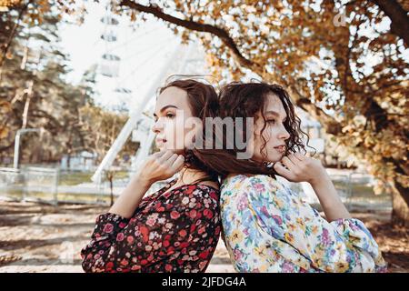 Zwei junge Frauen in Vintage-Kleidern stehen im Herbst umarmt parken Stockfoto
