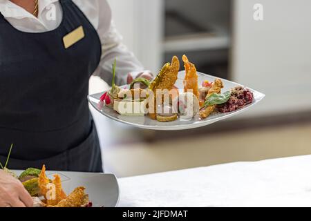 Kellnerin trägt Teller mit Vorspeise Stockfoto