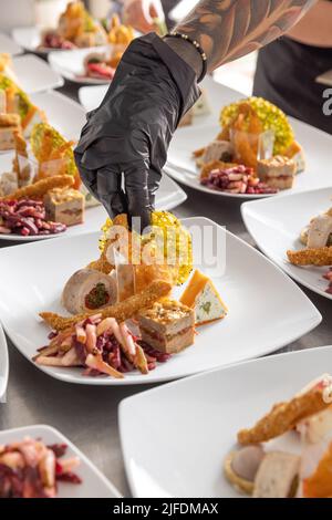 Der Koch garniert Vorspeisen auf der kommerziellen Küchentheke Stockfoto