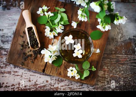 Grüner Jasmintee in einer Tasse. Jasminblüten, trockener Tee auf einer hölzernen Oberfläche. Stockfoto