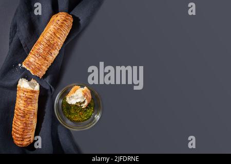Hausgemachtes, natürliches Weizenbrot. Gebrochenes frisches, knackiges französisches Baguette mit Olivenöl auf schwarzem Textilhintergrund mit Kopierfläche. Handgemachtes Backen. H Stockfoto