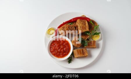 Jachnun oder Jahnun, jemenitisches jüdisches Gebäck, serviert mit frisch geriebenen Tomaten und gekochtem Ei und Zhug, aus den Adeni-Juden, und traditionell Stockfoto
