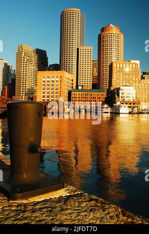 Die Wolkenkratzer von Rowes Wharf in Boston spiegeln sich im Wasser des Hafens, wie vom Poller am Fan Pier aus gesehen Stockfoto