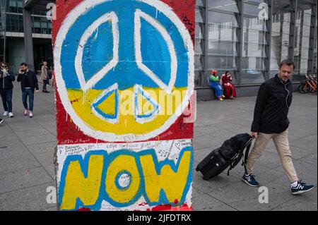 22.05.2022, Berlin, Deutschland, Europa - Originalwandsegment der ehemaligen Berliner Mauer, das ein Friedenssymbol in den ukrainischen Nationalfarben trägt. Stockfoto