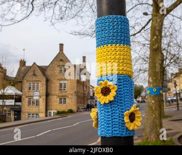 Nahaufnahme eines Strickstücks zur Unterstützung der Ukraine, auf einem Laternenpfosten in der historischen Marktstadt Chipping Norton in Oxfordshire, Großbritannien. Stockfoto